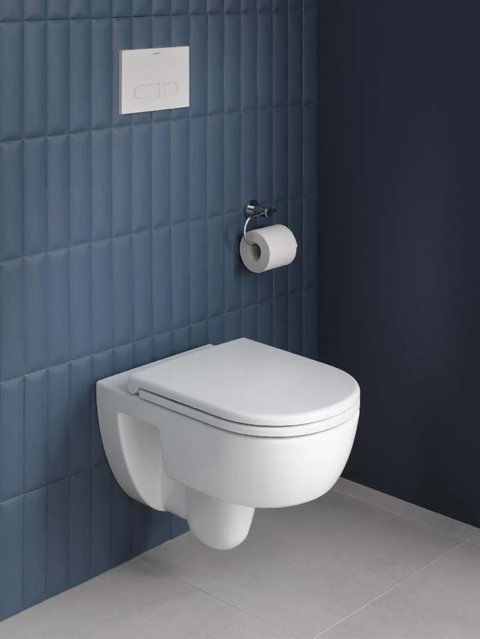 Wall-mounted toilet with paper holder at a blue tiled wall