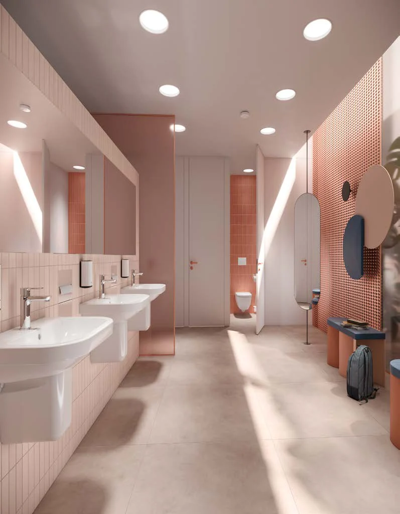 Public bathroom in blush pink with washing trough and partitions