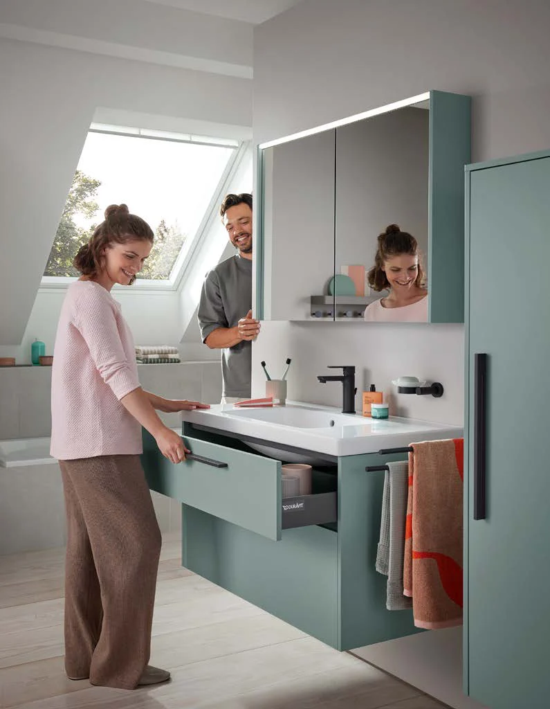 Couple opening a drawer of a green washbasin vanity