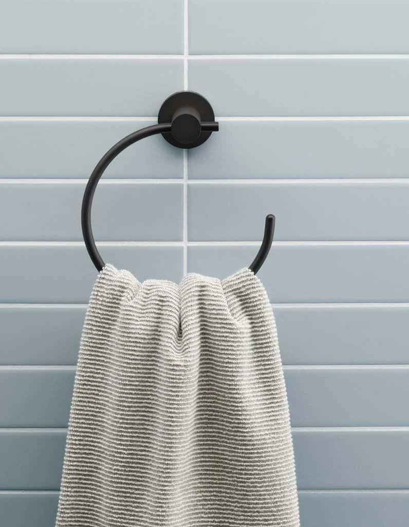 Black matt towel ring with towel at a light blue tiled wall