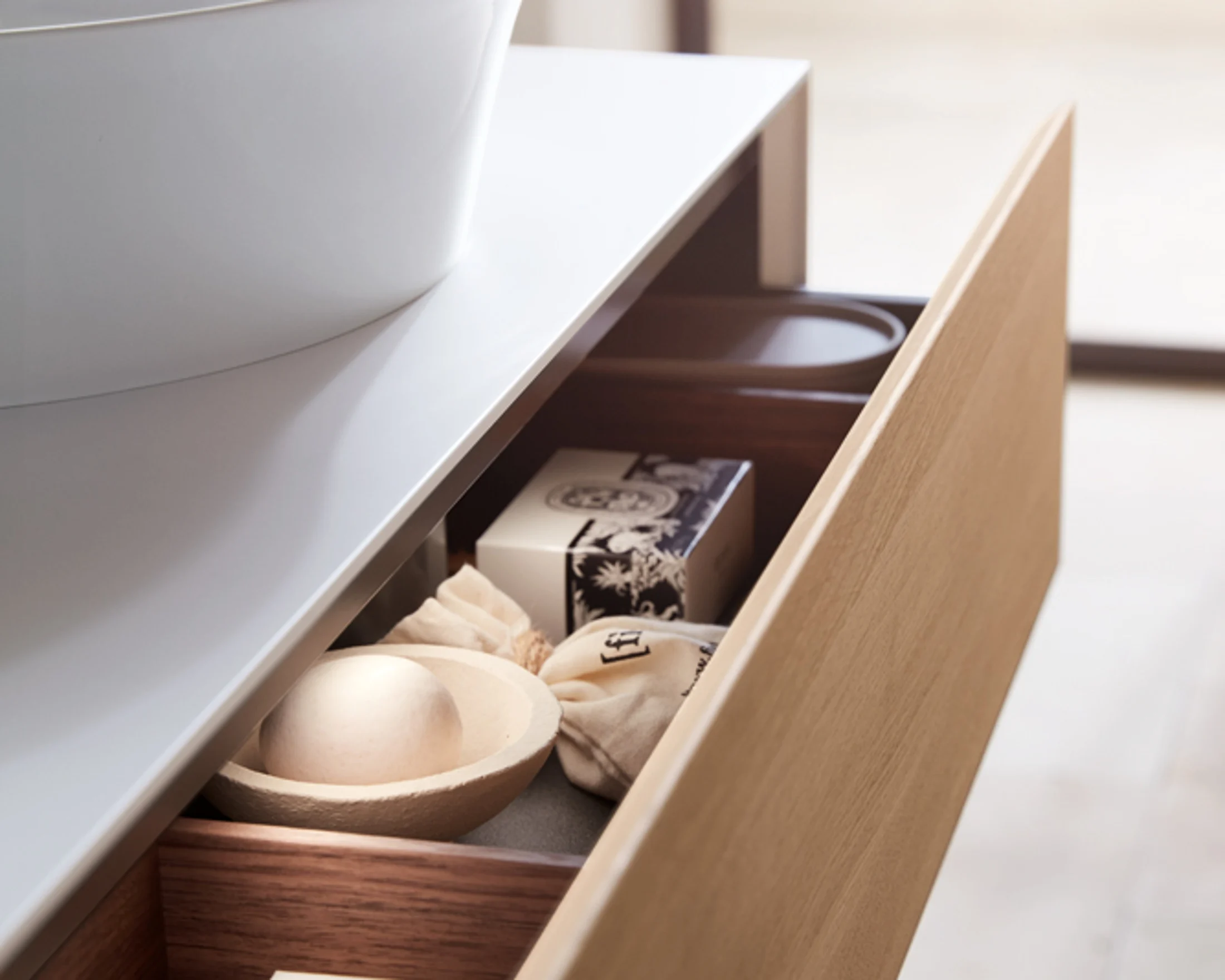 Open oak drawer with folded towels and bathroom accessories