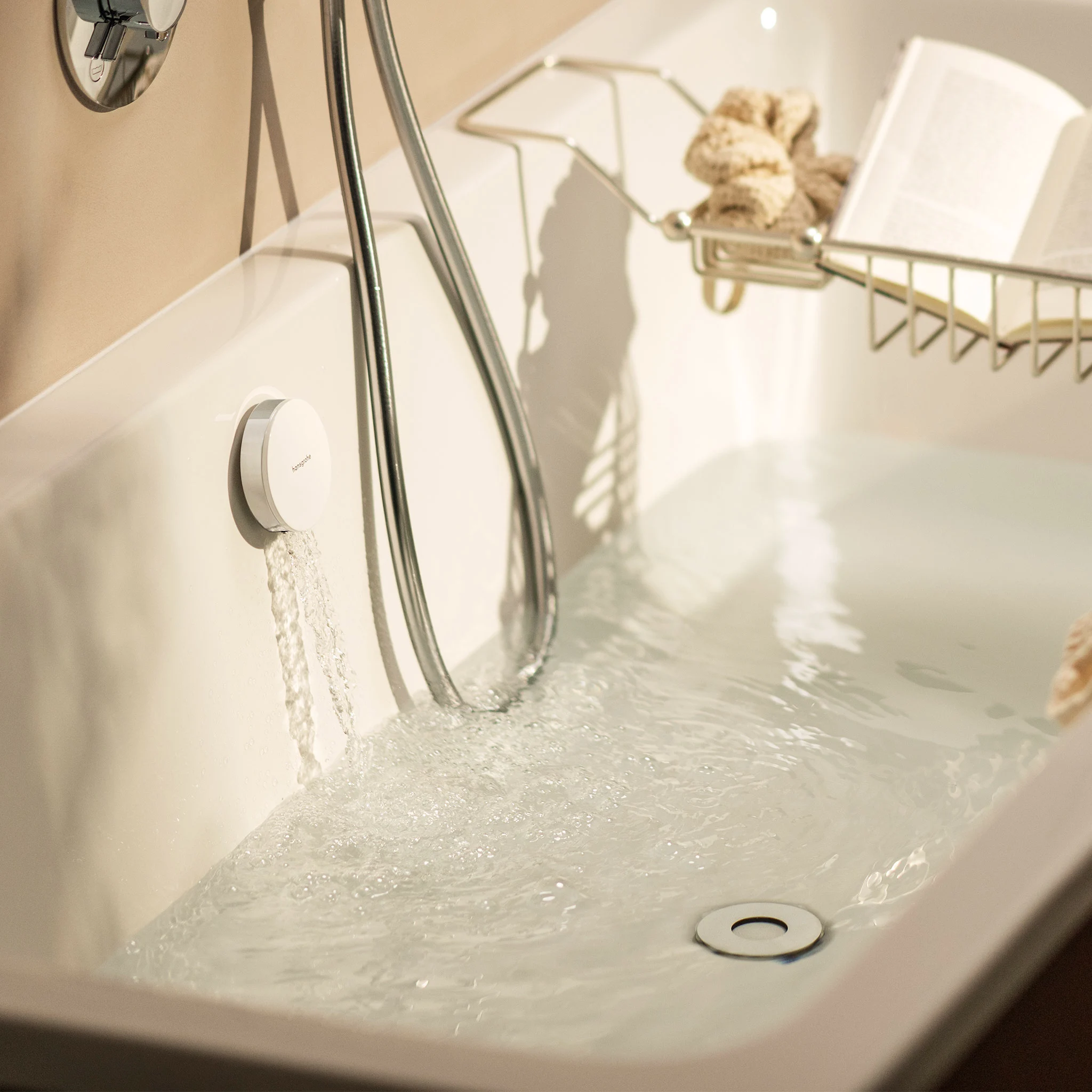 Bath filler pouring into a white tub in warm light