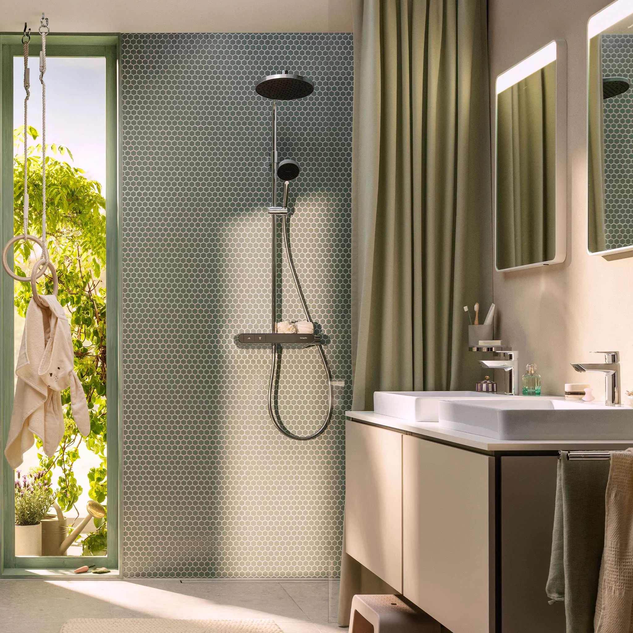 Sage penny-tile shower with a round chrome overhead by a sunny window